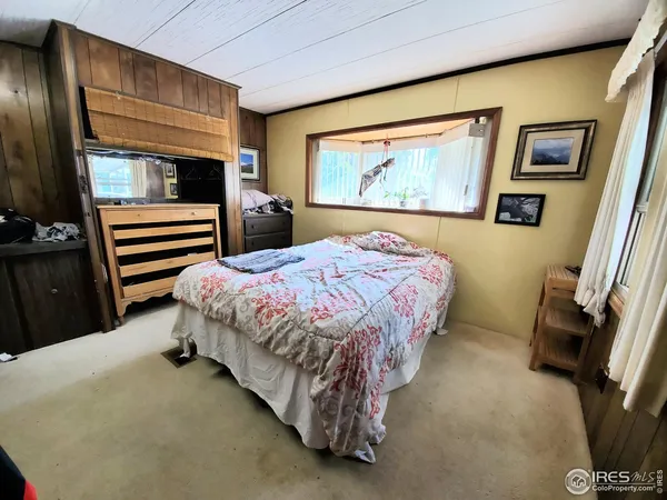 a bedroom with a bed painting on wall and a large window