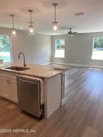 a kitchen with granite countertop a sink cabinets and wooden floor
