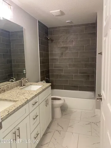 a bathroom with a granite countertop toilet a sink a mirror and shower