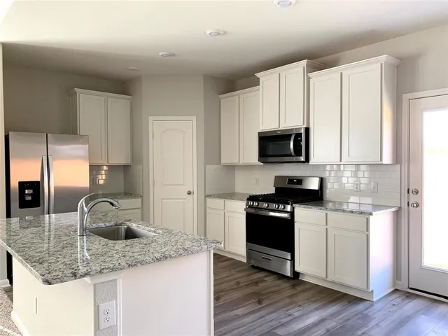 a kitchen with a refrigerator stove top oven and sink