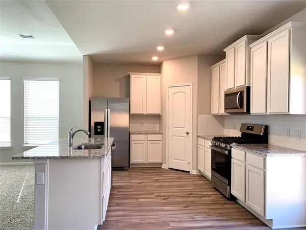 a kitchen with a sink wooden floor and stainless steel appliances
