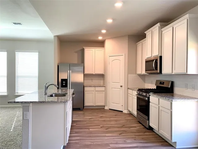 a kitchen with a sink wooden floor and stainless steel appliances
