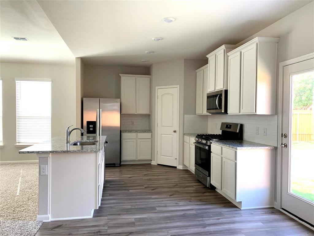 144 Emma Drive Anna, TX 75409 - Photo 13 of 34 a kitchen with a sink wooden floor and stainless steel appliances