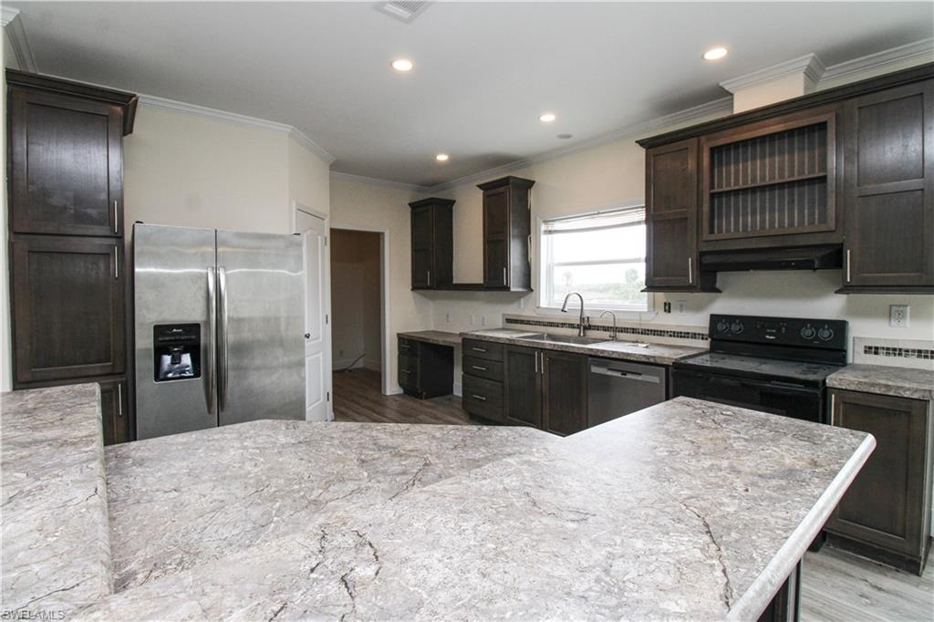 a kitchen with stainless steel appliances granite countertop a refrigerator a sink and a stove
