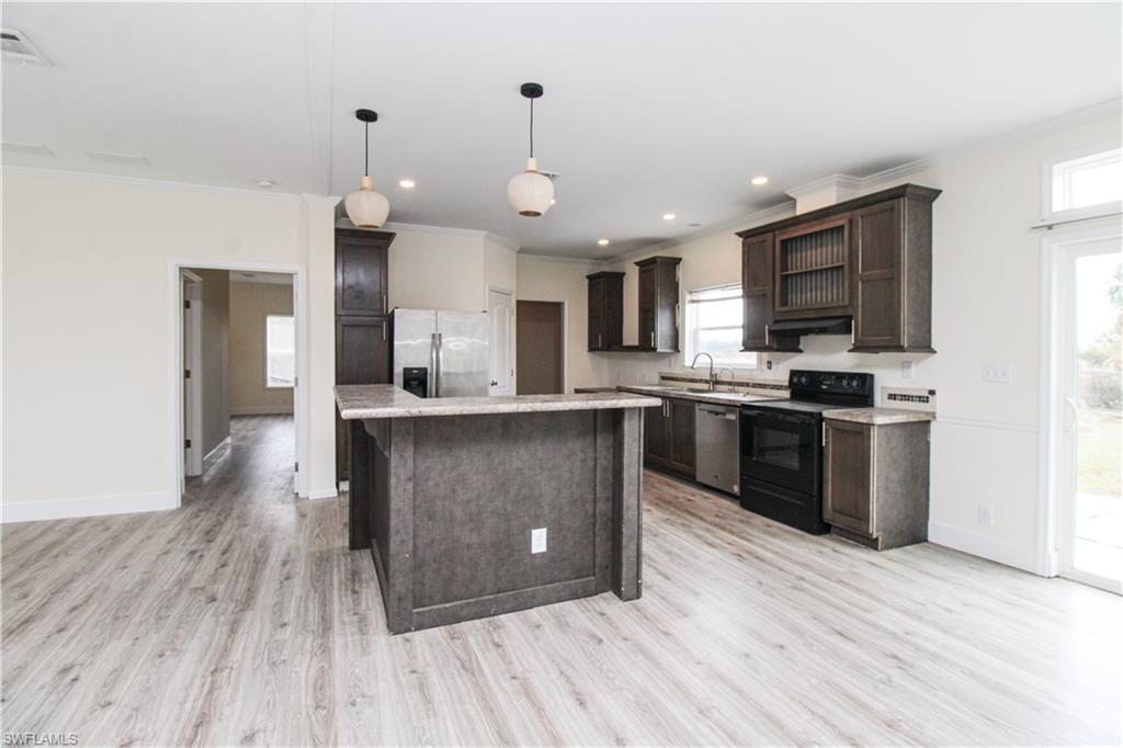 4660 43rd Avenue Northeast Naples, FL 34120 - Photo 11 of 44 a kitchen with stainless steel appliances kitchen island granite countertop a stove a sink and a refrigerator