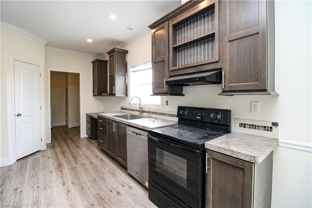 4660 43rd Avenue Northeast Naples, FL 34120 - Photo 13 of 44 a kitchen with stainless steel appliances granite countertop wooden cabinets a sink and a stove