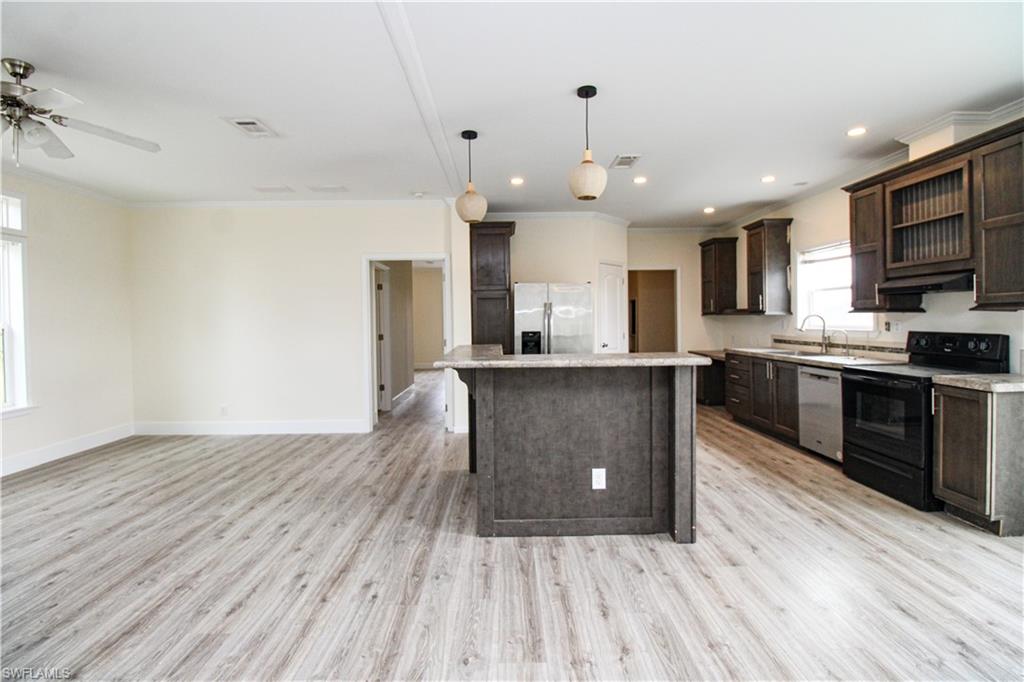 4660 43rd Avenue Northeast Naples, FL 34120 - Photo 15 of 44 a kitchen with stainless steel appliances granite countertop a sink a stove and a wooden floors