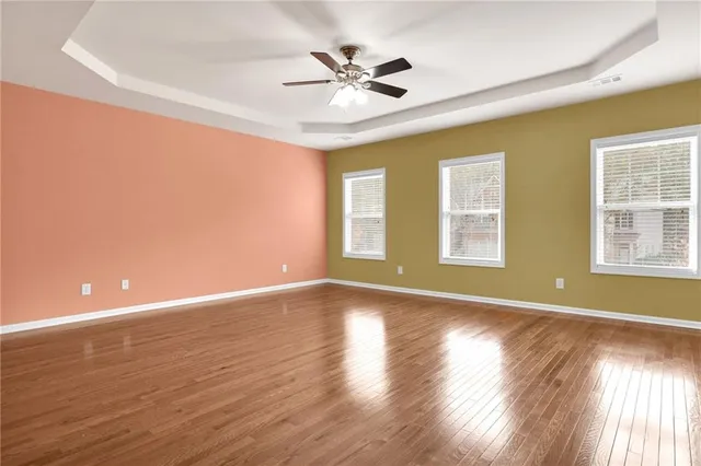 a view of an empty room with window and wooden floor