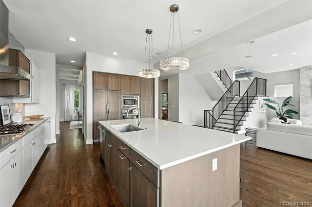 a large kitchen with kitchen island a stove a sink a refrigerator and a dining table with wooden floor