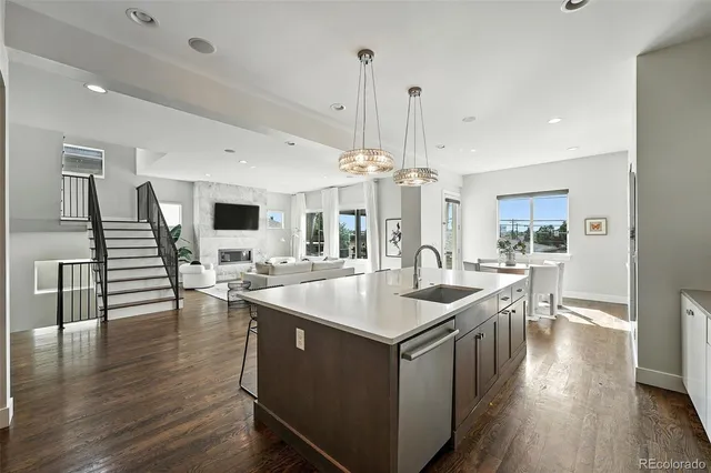 a kitchen with stainless steel appliances granite countertop a sink a stove and chairs with wooden floor