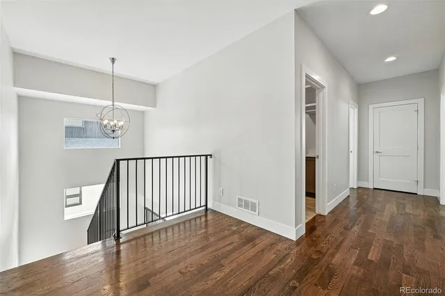a view of a hallway with wooden floor and a chandelier