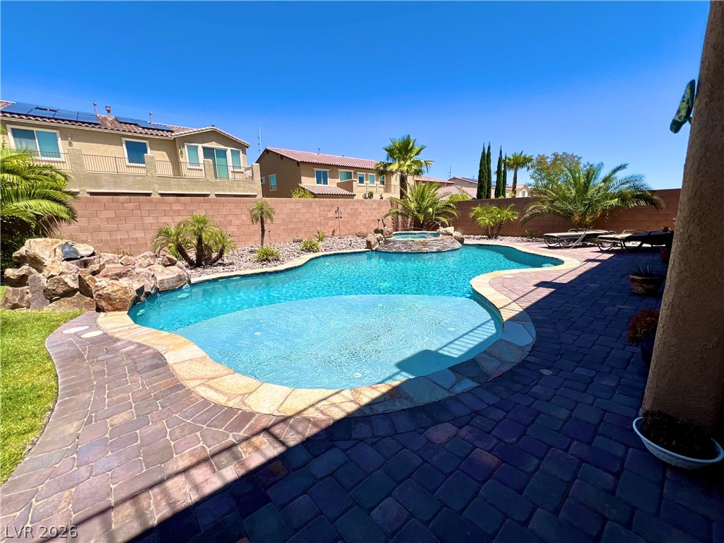 9724 University Ridge Avenue Las Vegas, NV 89149 - Photo 18 of 61 An inviting backyard oasis awaits with a sparkling pool, integrated spa, and vibrant landscaping.