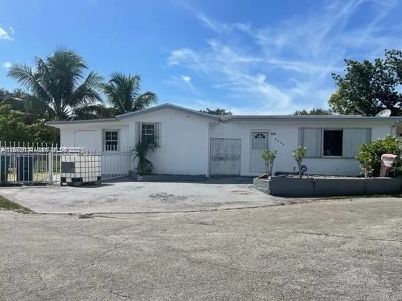 a view of a white house with a yard and potted plants
