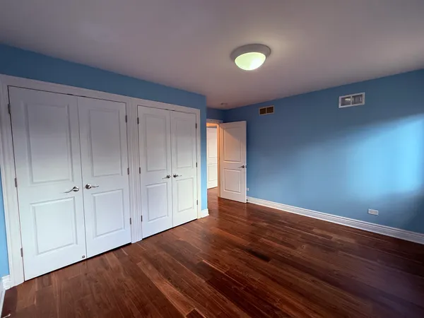 a view of an empty room with closet and wooden floor