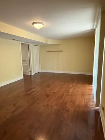 an empty room with wooden floor and windows with curtains
