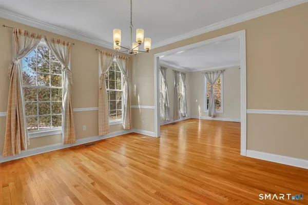a view of an empty room with window and wooden floor