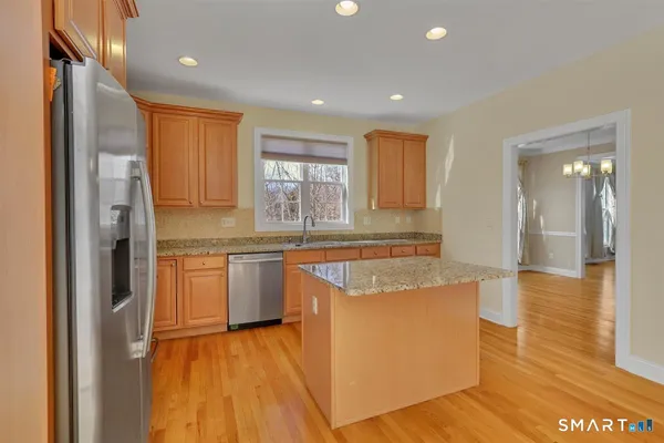 a kitchen with stainless steel appliances granite countertop a refrigerator a sink dishwasher and a stove with wooden floor