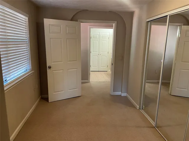 a view of an empty room with window and chandelier fan