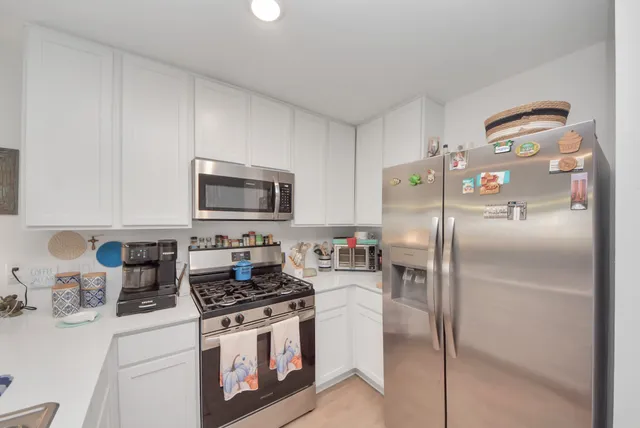 a kitchen with stainless steel appliances granite countertop a refrigerator a stove and a sink