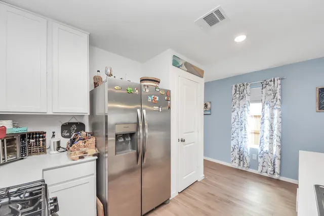 a kitchen with stainless steel appliances a refrigerator and wooden floor
