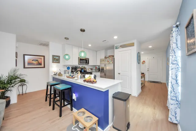 a kitchen with stainless steel appliances kitchen island granite countertop a refrigerator a stove a sink dishwasher and a dining table with wooden floor