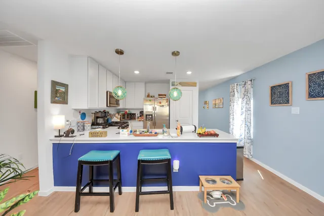 a room with stainless steel appliances kitchen island granite countertop a sink a stove a dining table and chairs