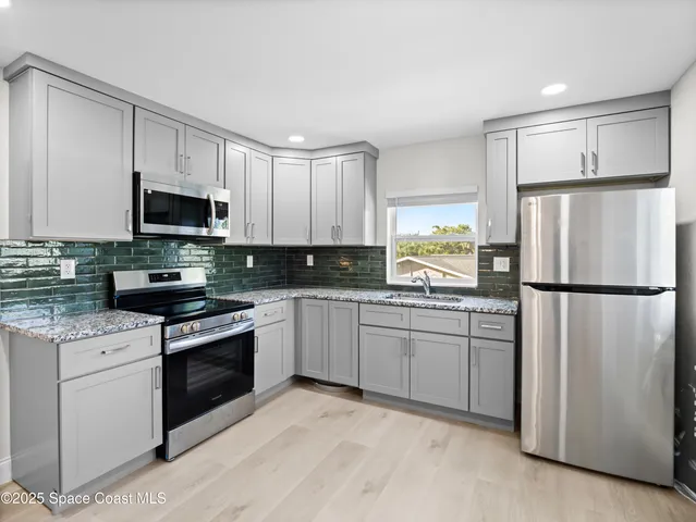 a kitchen with granite countertop white cabinets and refrigerator