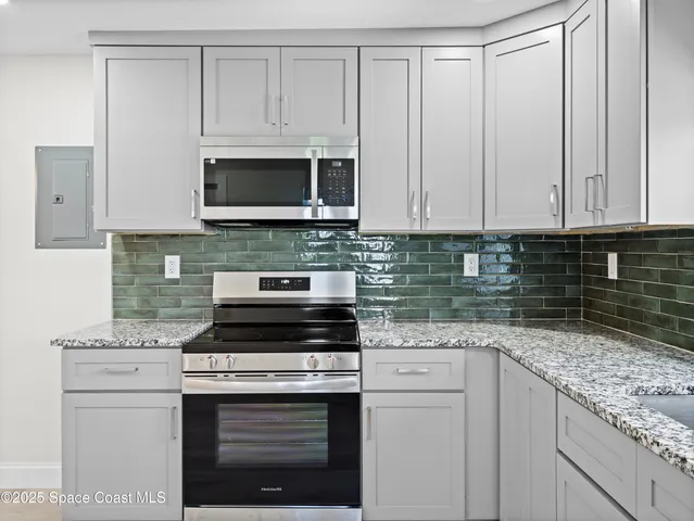 a kitchen with granite countertop white cabinets and a stove a oven with white countertops