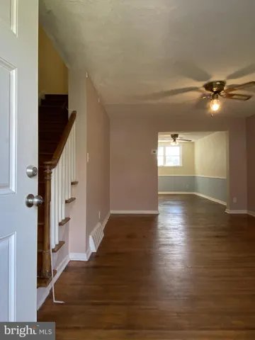 a view of an empty room with wooden floor and staircase