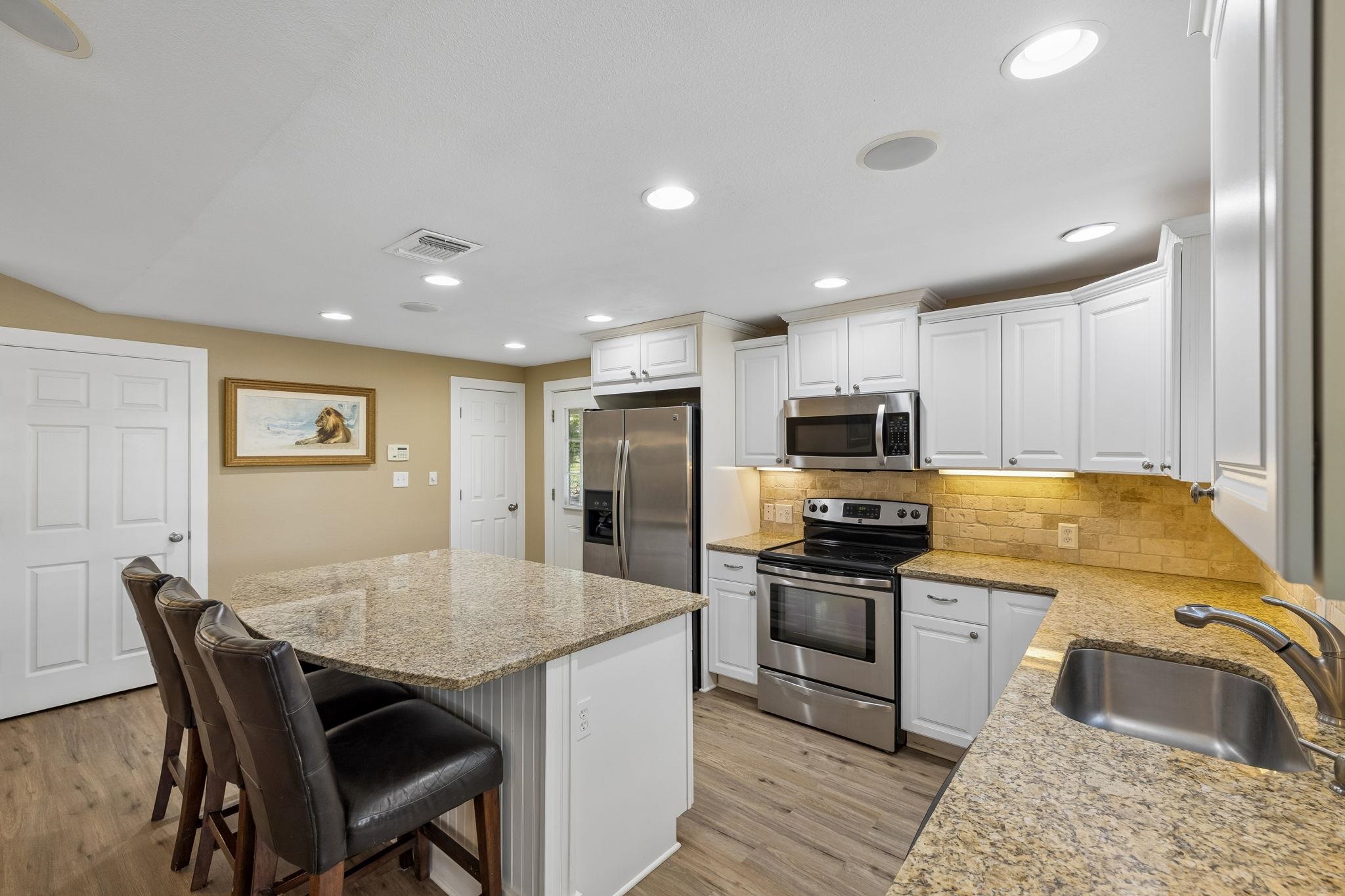 230 Lee Street Seguin, TX 78155 - Photo 18 of 40 a kitchen with granite countertop kitchen island stainless steel appliances a stove a sink a refrigerator cabinets and a dining table