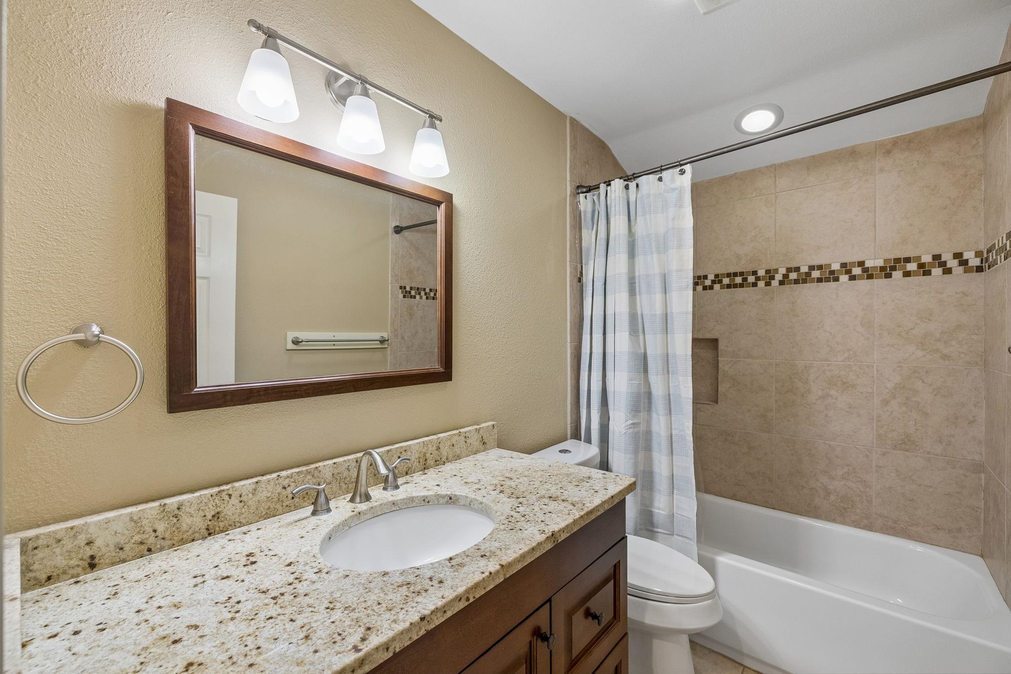 230 Lee Street Seguin, TX 78155 - Photo 24 of 40 a bathroom with a granite countertop sink a mirror a bathtub and shower