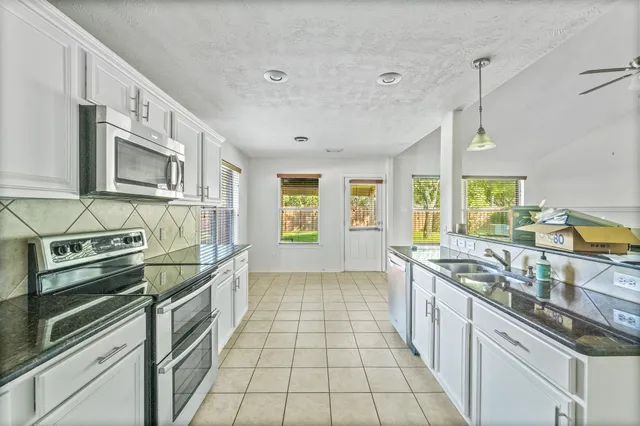 a kitchen with stainless steel appliances granite countertop a stove a sink and a microwave