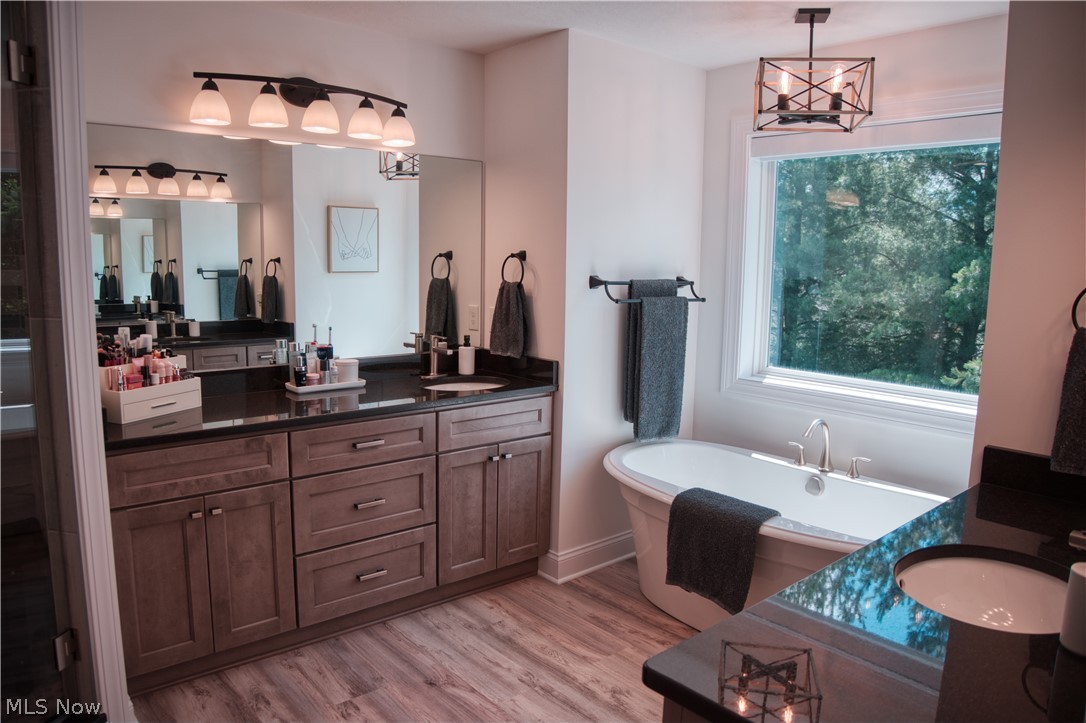4553 Sharon Copley Road Medina, OH 44256 - Photo 9 of 32 Spacious bathroom featuring a freestanding soaking tub, dual vanity with dark countertops, and wood-finish flooring