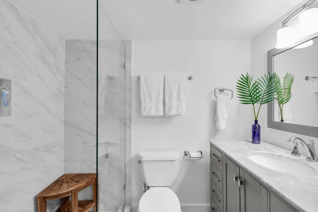 a bathroom with a granite countertop sink a toilet and shower