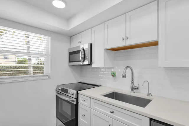 a kitchen with stainless steel appliances granite countertop a sink a stove and a microwave oven