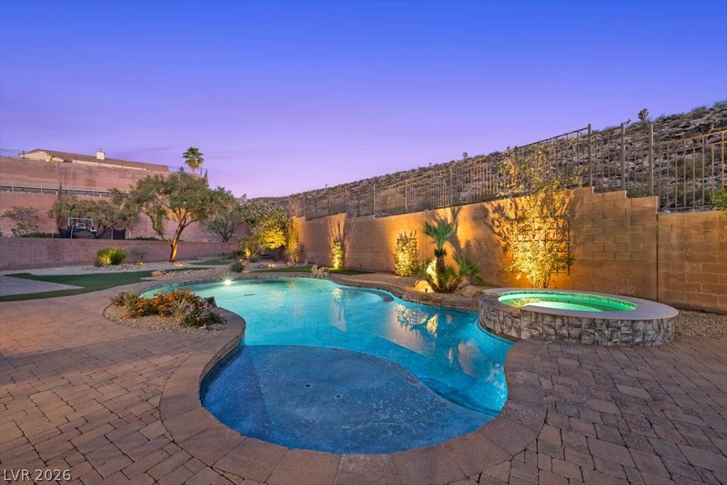 2125 De Rouge Avenue Henderson, NV 89044 - Photo 16 of 96 An inviting backyard oasis offers a sparkling pool, integrated spa, and illuminated landscaping.