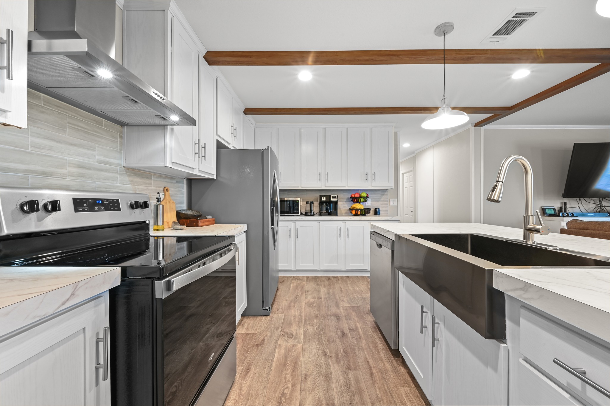 117 Castellana Way Elgin, TX 78621 - Photo 11 of 28 Kitchen featuring stainless steel appliances, backsplash, white cabinetry, light wood finished floors, and crown molding