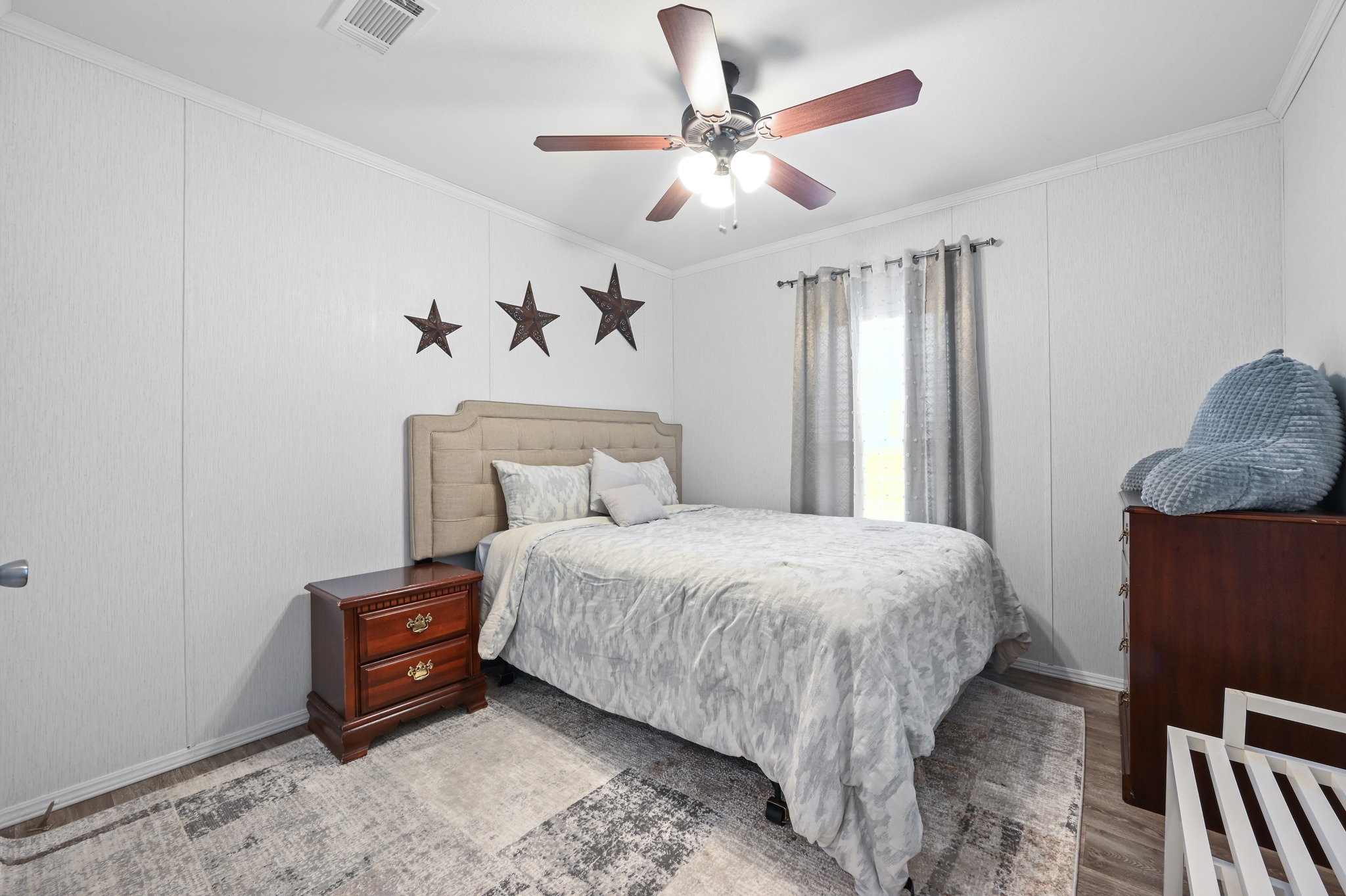 117 Castellana Way Elgin, TX 78621 - Photo 16 of 28 Bedroom with a decorative wall, ornamental molding, a ceiling fan, and wood finished floors