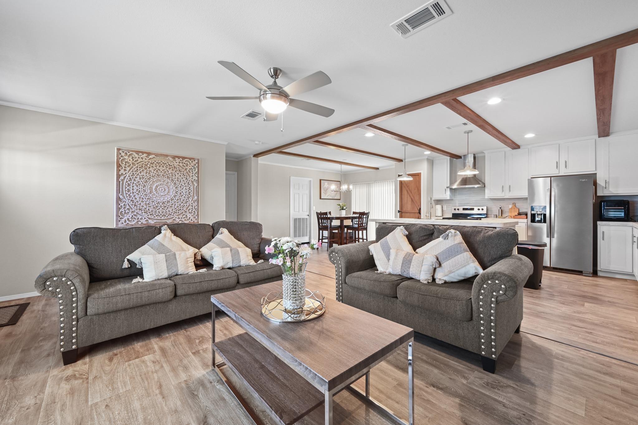 117 Castellana Way Elgin, TX 78621 - Photo 5 of 28 Living area with beamed ceiling, a ceiling fan, light wood-style flooring, and a chandelier