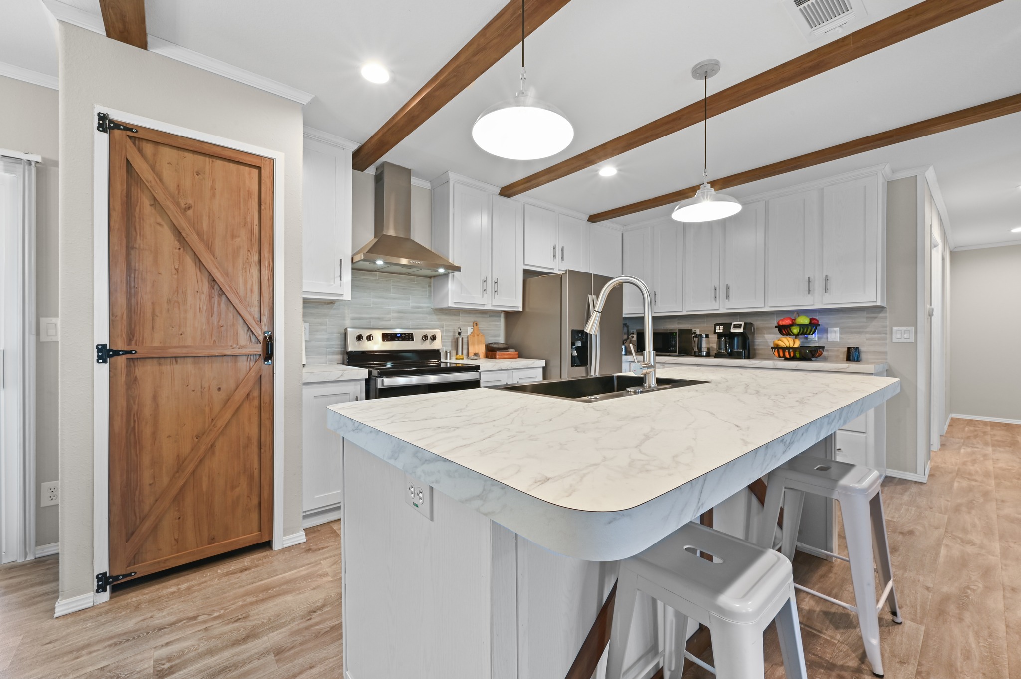 117 Castellana Way Elgin, TX 78621 - Photo 9 of 28 Kitchen featuring light countertops, a barn door, a breakfast bar, white cabinetry, and crown molding
