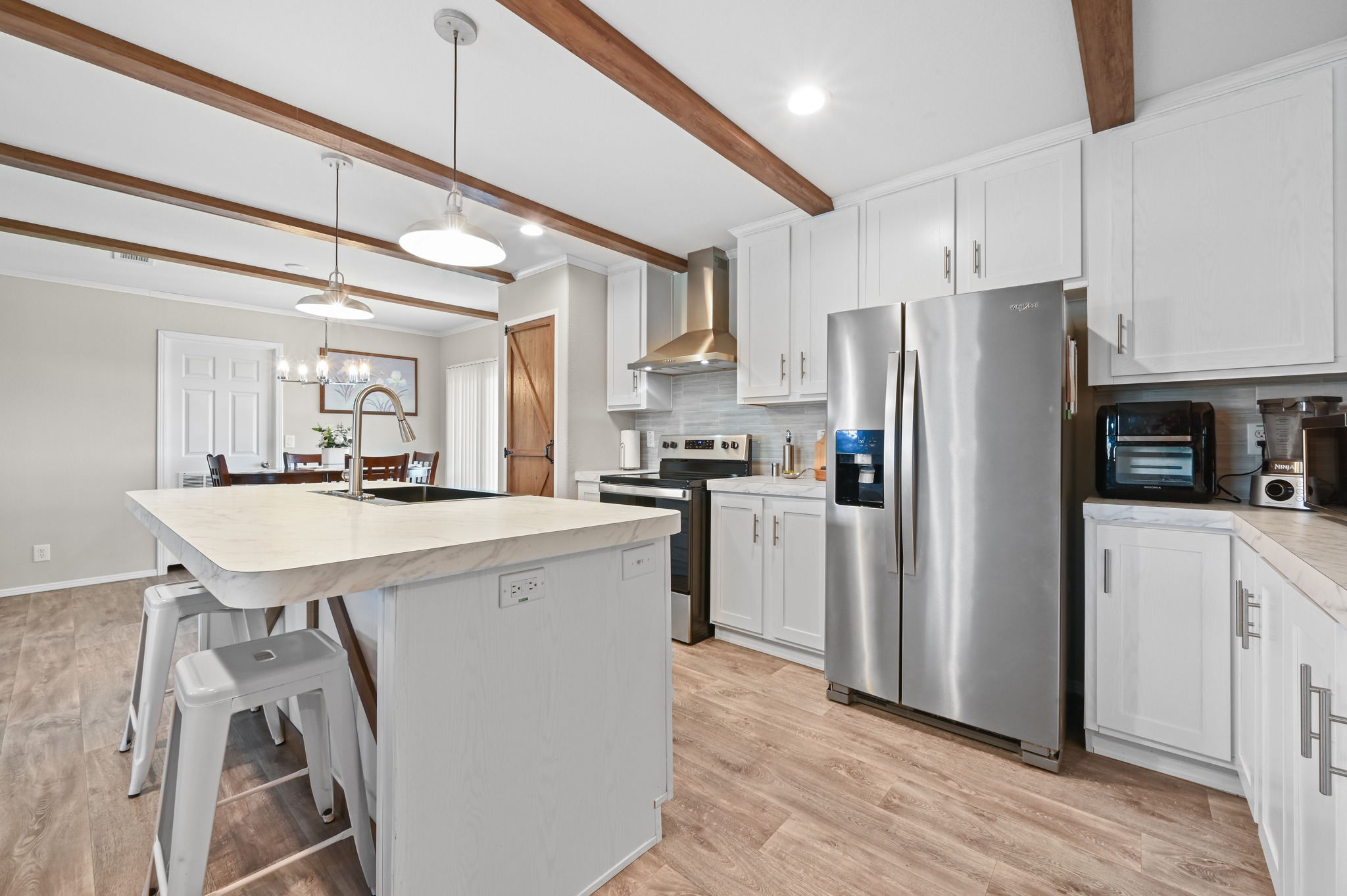 117 Castellana Way Elgin, TX 78621 - Photo 10 of 28 Kitchen with light countertops, stainless steel appliances, an island with sink, white cabinets, and a kitchen bar