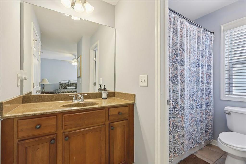 4460 Granby Circle Cumming, GA 30041 - Photo 22 of 34 a bathroom with a granite countertop sink a toilet a mirror and shower