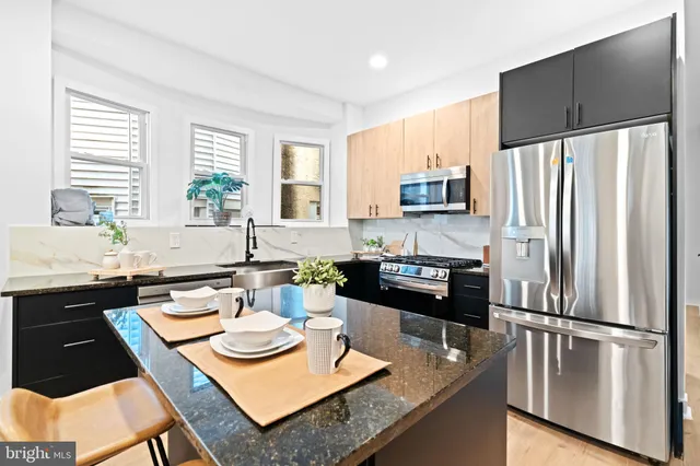 a kitchen with granite countertop a sink refrigerator and cabinets