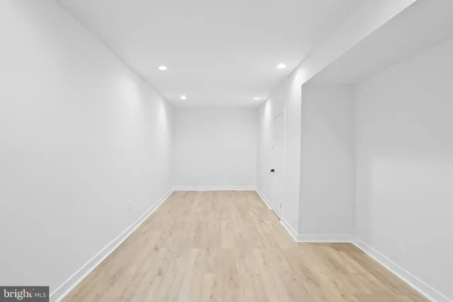 a view of a hallway with wooden floor and a bathroom
