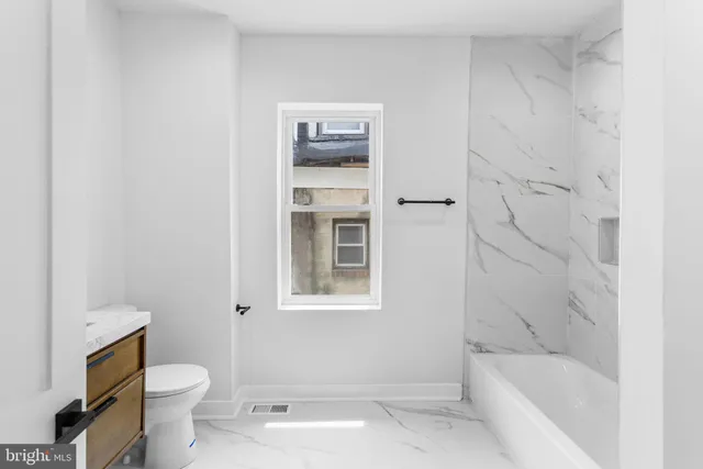 a view of an empty room with wooden floor and window