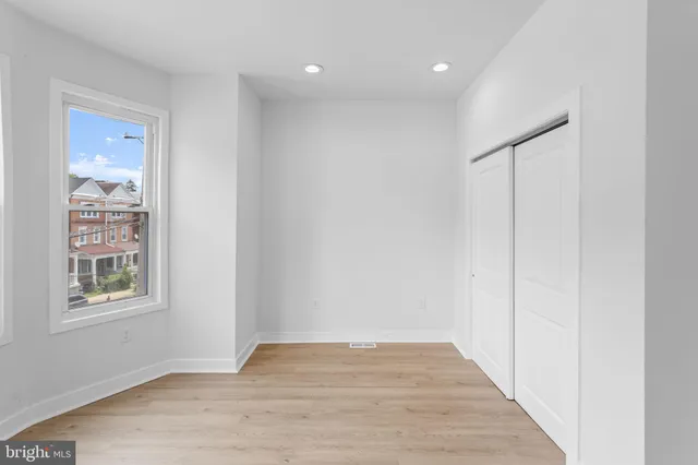 a view of a hallway with wooden floor and a bathroom