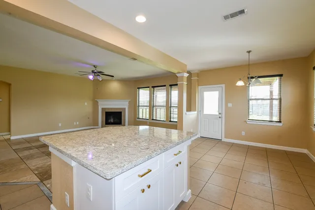 a view of an empty room and window and chandelier fan