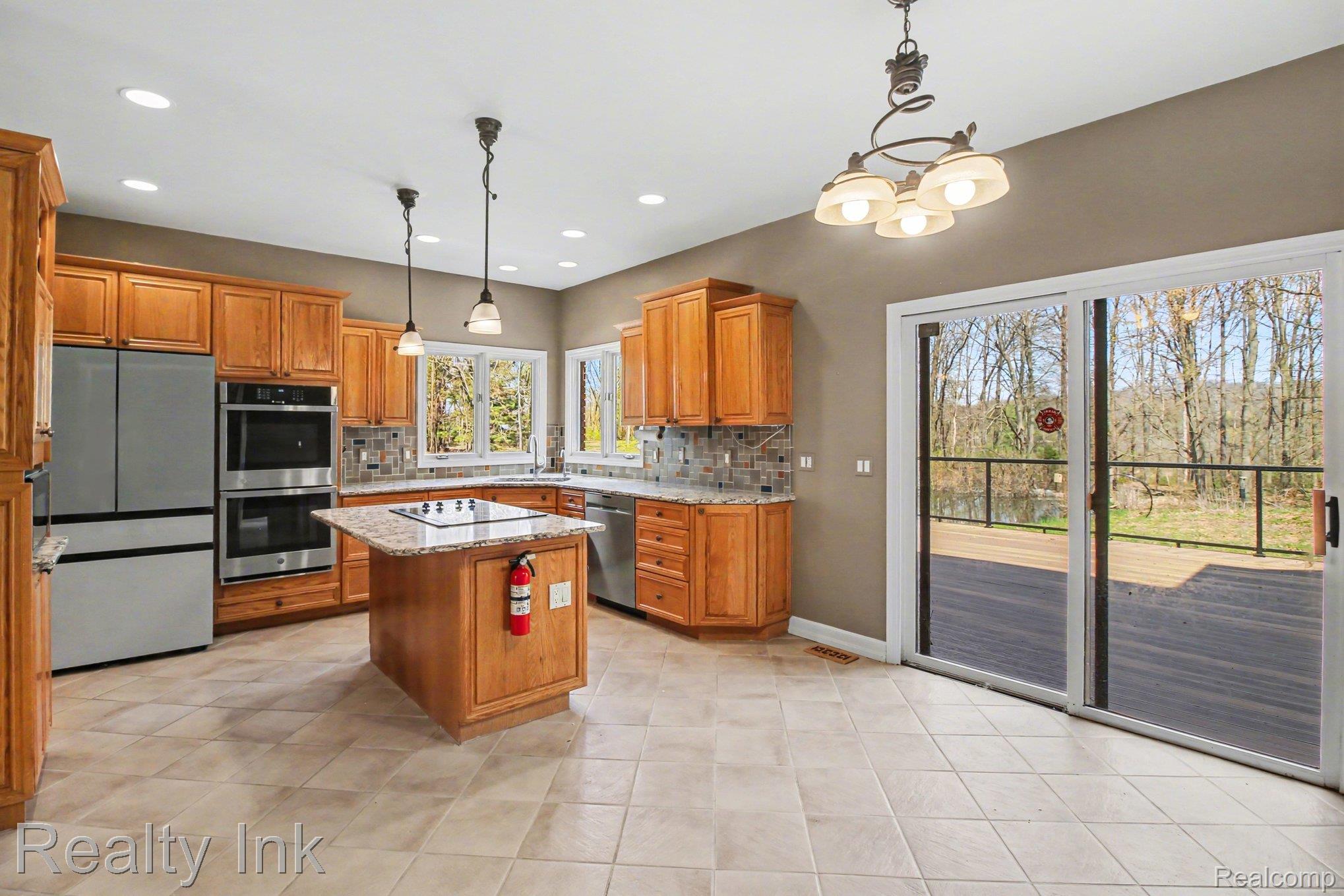 4927 Nature View Court Howell, MI 48843 - Photo 8 of 19 Kitchen featuring wood finish cabinets, light stone countertops, stainless steel appliances, and a center island