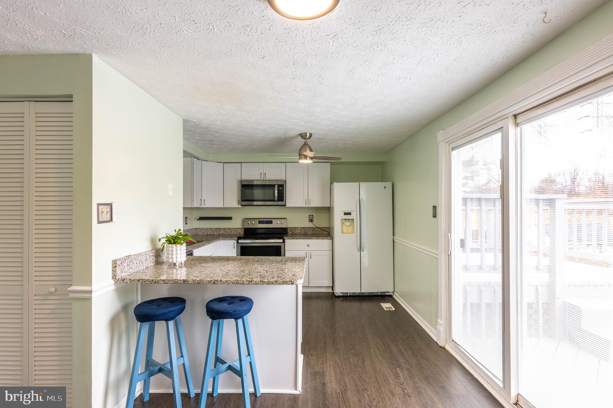 27 Cavan Green Nottingham, MD 21236 - Photo 11 of 31 a kitchen with stainless steel appliances kitchen island granite countertop a stove a sink and a refrigerator with wooden floor