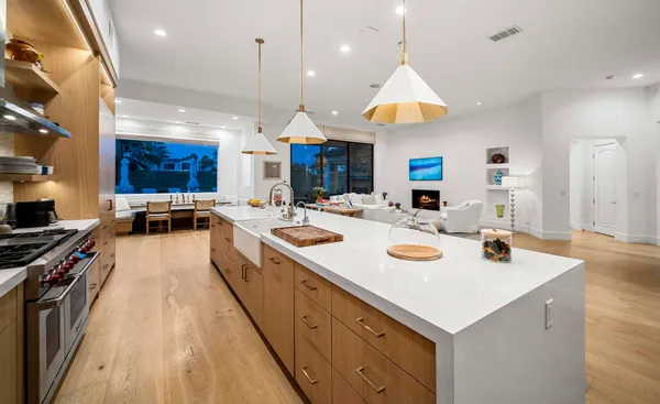 a kitchen with stainless steel appliances a stove a sink dishwasher and a dining table with wooden floor